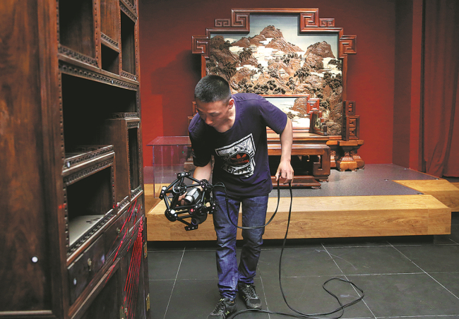 A staff member of the Palace Museum takes measurements of a piece of royal furniture from the Qing Dynasty (1644-1911) on Friday. [Photo: China Daily]
