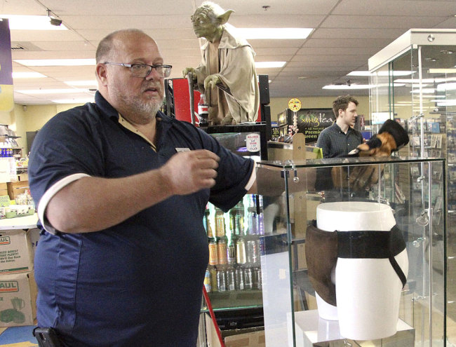 In this May 2, 2018 file photo, Blockbuster Alaska General Manager Kevin Daymude moves a display case featuring the jockstrap worn by actor Russell Crowe in the 2005 movie "Cinderella Man" at a Blockbuster video store in Anchorage, Alaska. Despite the gift of the jockstrap from HBO's John Oliver to bring traffic into the store, Daymude said the last two Blockbuster Video locations in Alaska will rent their last video on Sunday, July 15, 2018, apparently leaving the last Blockbuster Video in Bend, Ore. [File photo: AP/Mark Thiessen]