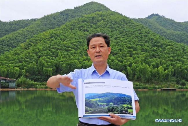 Pan Wenge, secretary of the Communist Party of China local branch in the Yucun Village, shows the plans to upgrade the village to a 5A tourist destination, in Yucun Village of Anji County, east China's Zhejiang Province, June 2, 2018. In 2017, there were an estimated 400,000 visitors from home and abroad to Yucun. [Photo:Xinhua/Tan Jin]