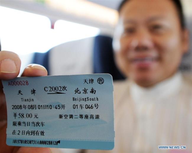 A passenger shows a train ticket(火车票) for the Beijing-Tianjin high-speed intercity train in north China's Tianjin Municipality, Aug. 1, 2008. (Xinhua/Wang Yebiao)