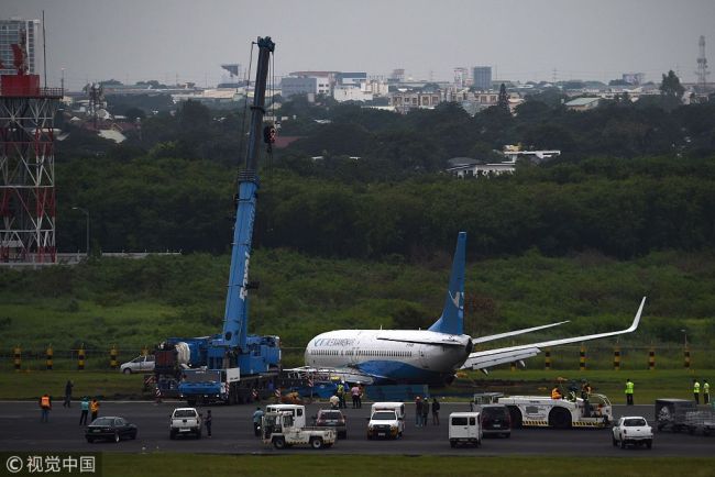 A crane prepares to lift a Xiamen Air Boeing 737-800 series passenger aircraft, operating as flight MF8667 from Xiamen to Manila, after it skidded off the runway while attempting to land in bad weather at the Manila international airport on August 17, 2018. [Photo: VCG]