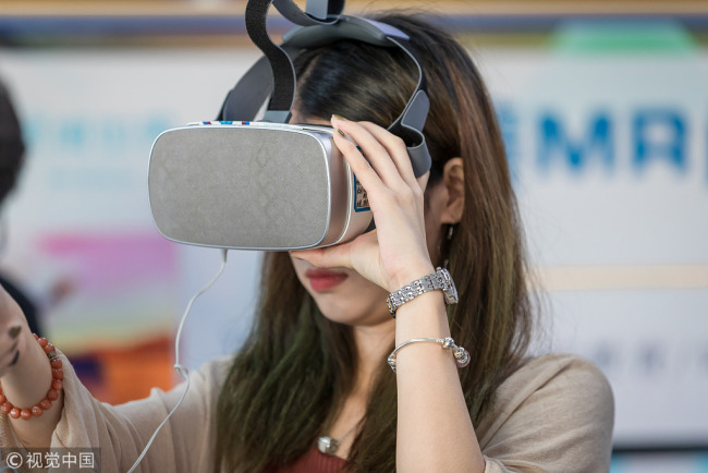 A woman wears a virtual reality headset. [File Photo: VCG]