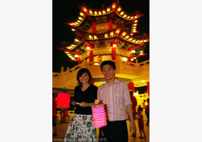 The picture shows a couple holding lanterns during Mid-Autumn Festival celebrations, at a temple in Kuala Lumpur, Malaysia, Sept 25, 2007. [Photo/IC]