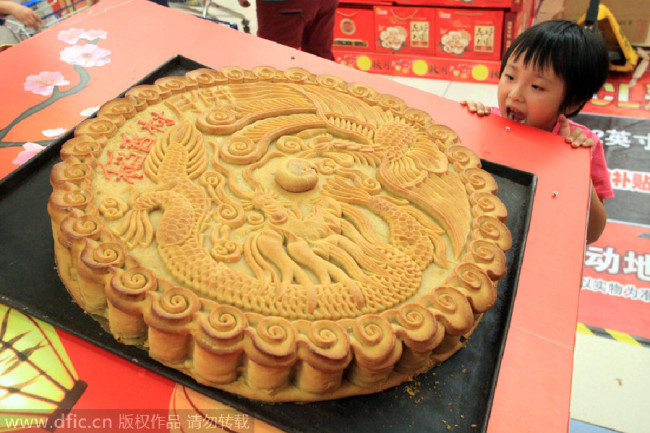 A child stares at a large mooncake(月饼). [Photo/IC]