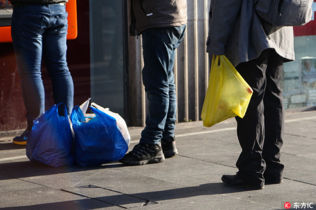 Photo taken on January, 10, 2018 show pedestrians carrying plastic bags in London, UK. The UK Government launched a consultation on extending 5p plastic bag charge to smaller shops with less than 250 staff to tackle Britain in January, 2018. [Photo: IC]
