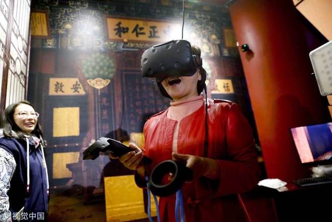 A visitor has an immersive experience using a VR headset during a digital exhibition at the Palace Museum in Beijing on October 10, 2017. [Photo: VCG]