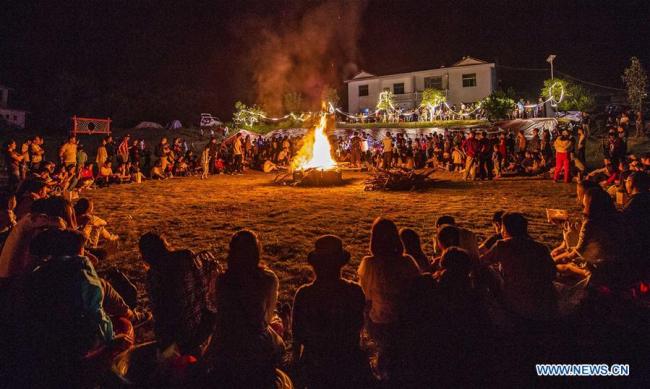 Tourists(游客) take part in(参加) a bonfire music festival in Quantian Village of Jiulongshan Township, Xinyu, east China's Jiangxi Province, Oct. 1, 2018. (Xinhua/Zhao Chunliang)