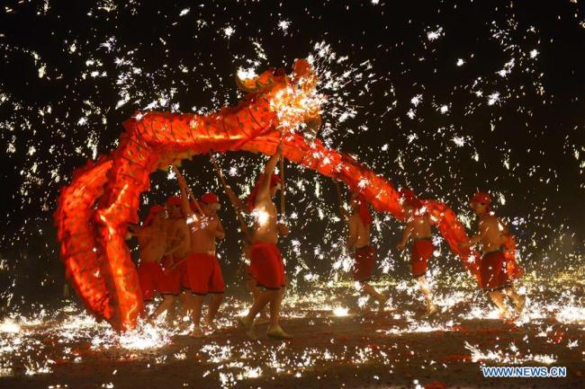 Folk artists(艺术家) perform(表演) a dragon dance amid showers of molten iron in Xiushui Village of Longchang Township in Puding County, southwest China's Guizhou Province, Oct. 3, 2018. (Xinhua/Qin Gang)