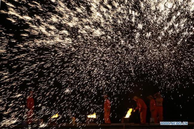 Folk artists from northwest China's Shanxi Province stage an alternative fireworks(烟花) show by splashing molten iron(铁水) into the air in Huaibei, east China's Anhui Province, Oct. 1, 2018.(Xinhua/Wan Shanchao)