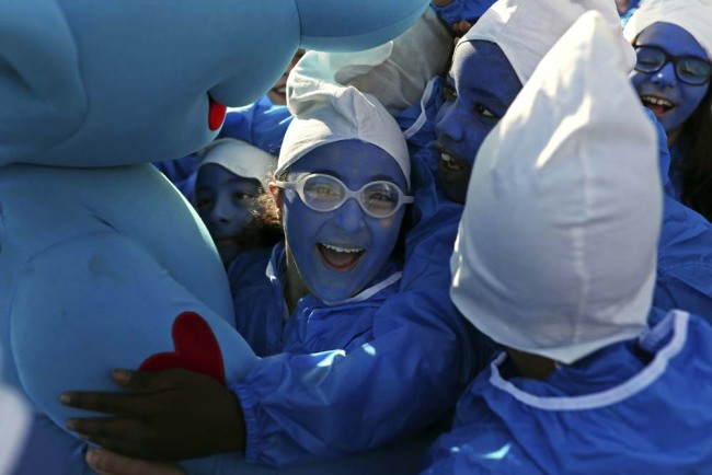 Children dressed as Smurfs hug a person wearing a Smurf costume during a Smurfs exhibition marking the 60th anniversary of their creation by Belgium cartoonist Pierre Culliford, known as Peyo, in Brussels, Tuesday, Oct. 23, 2018. [Photo: AP]