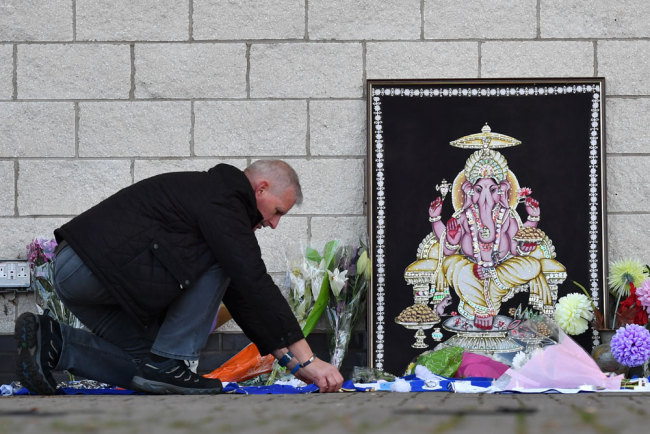 A man adds to flowers and Leicester City scarfs left as tributes outside Leicester City Football Club's King Power Stadium in Leicester, eastern England, on October 28, 2018 after a helicopter belonging to the club's Thai chairman Vichai Srivaddhanaprabha crashed outside the stadium the night before. [Photo: AFP/Ben Stansall]