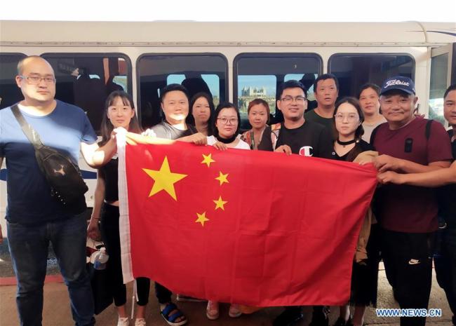 Chinese tourists pose with Chinese national flag before starting to fly back home in Saipan, the Commonwealth of the Northern Mariana Islands (CNMI), Oct. 28, 2018. Some 1,500 Chinese tourists trapped in Saipan by Super Typhoon Yutu started to fly back home on Sunday. [Photo: Xinhua]