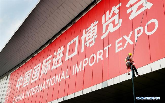A worker pastes a sign poster for the upcoming China International Import Expo (CIIE) at the National Exhibition and Convention Center in Shanghai, Oct. 26, 2018. [Photo: Xinhua]