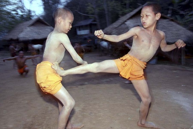 In this March 19, 2002, file photo, two novice Buddhist monks practice Muay Thai (Thai kickboxing) during a morning training session at the Golden Horse Monastery in northern Thailand. The death of a 13-year-old boy who was knocked out during a Muay Thai boxing match in Thailand has sparked debate over whether to ban child boxing. [File photo: AP]