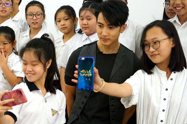 Famous Bruneian singer and actor Wu Chun (Center) goes back to his Alma Mater, the Chung Hwa Middle School in Brunei, and takes a group photo with the students and teachers on November 15th, 2018. [Photo: VCG]