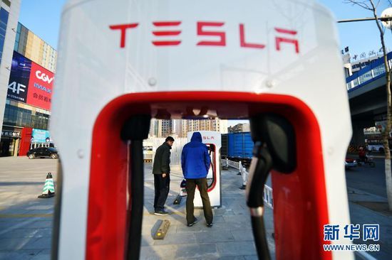 Two people check out a Tesla charging pile at a parking lot in Shenyang, Liaoning Province. [File Photo: Xinhua]