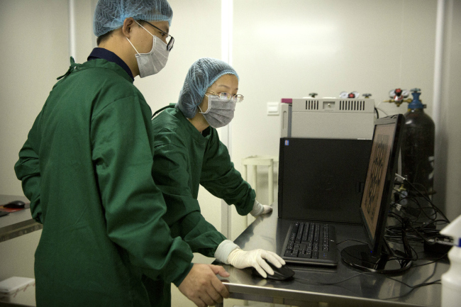 Qin Jinzhou, left, and Zhou Xiaoqin look at a monitor in a laboratory in Shenzhen on October 9, 2018. [Photo: AP]