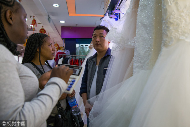 Buyers communicate(交流 jiāoliú) with shop owners(店主 diànzhǔ) at a wedding dress market(市场 shìchǎng) in in Guangzhou, Guangdong Province on November 26.[Photo: VCG]