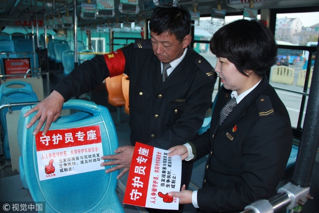 A "Driver's Guardian" seat being prepared by two bus company employees on a bus in Qingdao. [File Photo: VCG]