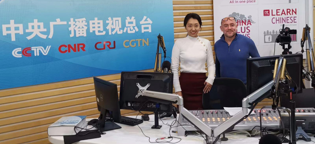 CRI host Liu Mohan (left) and director Adam Stafford (right) pose together after an interview on Dec. 10, in the radio station's studio. [Photo:China Plus]
