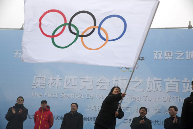 Han Zirong, secretary-general of the Beijing 2022, waves the Olympic flag during a ceremony to mark the arrival of the Olympic flag and start of the flag tour for the Winter Olympic Games Beijing 2022 at a section of the Great Wall of China on the outskirts of Beijing Tuesday, Feb. 27, 2018. (AP Photo/Ng Han Guan)