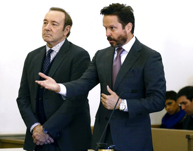 Actor Kevin Spacey stands in district court as his attorney Alan Jackson, right, addresses the judge during arraignment on a charge of indecent assault and battery on Monday, Jan. 7, 2019, in Nantucket, Mass. The Oscar-winning actor is accused of groping the teenage son of a former Boston TV anchor in 2016 in the crowded bar at the Club Car in Nantucket. [Photo: The Inquirer and Mirror via AP, Pool/Nicole Harnishfeger]