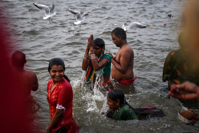 Indian devotees take a dip on the banks of the Triveni Sangam, the confluence of the Ganges, Yamuna and mythical Saraswati rivers, as people gather for the Kumbh Mela festival in Allahabad on January 14, 2019. [Photo: AFP/Chandan Khanna]