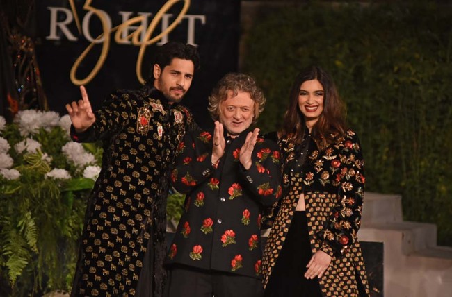 Indian Bollywood actors Siddharth Malhotra (L) and Daina Penty (R) gesture during the fashion show by designer Rohit Bal at the Blenders Pride Fashion Tour in Mumbai on January 16, 2019. [Photo: AFP]