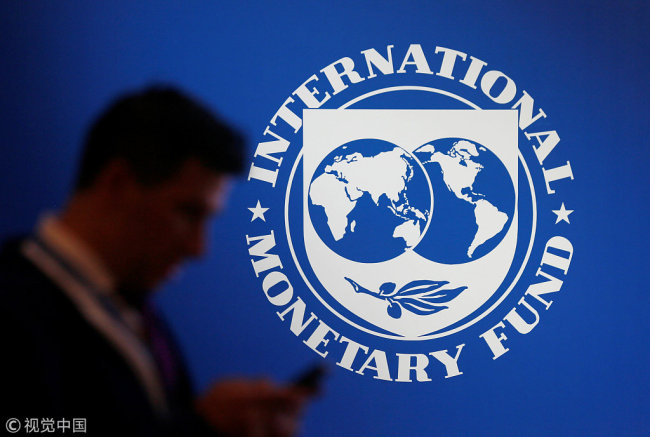 A participant stands near a logo of IMF at the International Monetary Fund - World Bank Annual Meeting 2018 in Nusa Dua, Bali, Indonesia, October 12, 2018. [Photo: VCG]