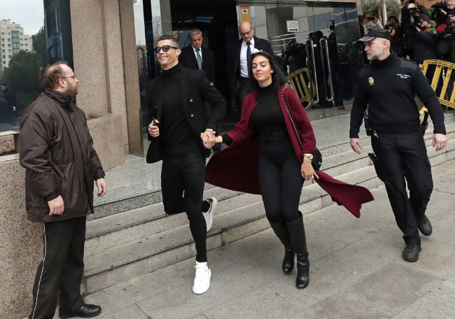 Cristiano Ronaldo leaves the court in Madrid with his girlfriend Georgina Rodriguez on Tuesday, Jan. 22, 2019. Cristiano Ronaldo is expected to plead guilty to tax fraud. The Juventus forward arrived in a black van, walked up some stairs leading to the court house and stopped to sign an autograph. The charges stem from his days at Real Madrid. [Photo: AP/Manu Fernandez]
