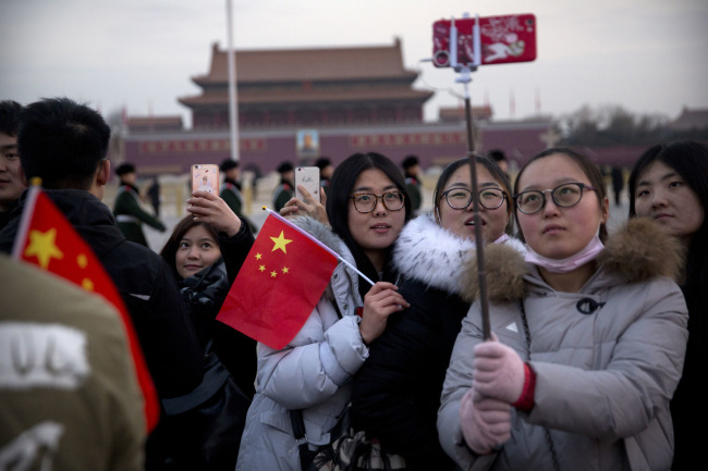 Tourists pose for selfies on Tiananmen Square in Beijing, Monday, March 5, 2018. [Photo: AP Photo/Mark Schiefelbein]