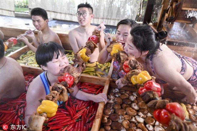 Visitors enjoy kebabs(烤串 kǎo chuàn) in the nine-grid hotpot-shaped hot spring pool filled with vegetables and fruits at a hotel in Hangzhou, east China's Zhejiang province, January 27, 2019. [Photo: IC]