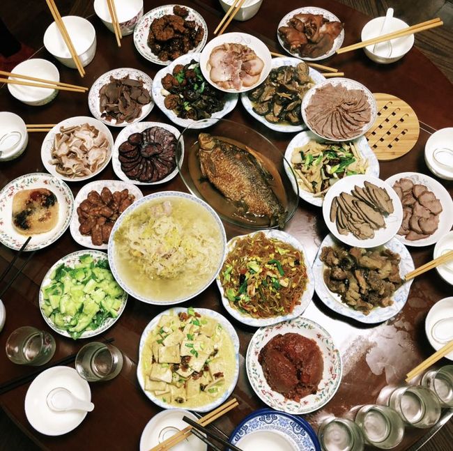 A photo, taken on February 4, 2019, Lunar New Year's Eve, showing a family reunion in Hubei Province. Two main dishes are at the center of the table. One is a soup dish made up of pork and Suancai, or pickled cabbage. The other is a fish dish, considered a must-have in Hubei, which is intersected by the Yangtze River. Fish is said to represent abundance for the new year. [Photo: China Plus/Hu Yijing]