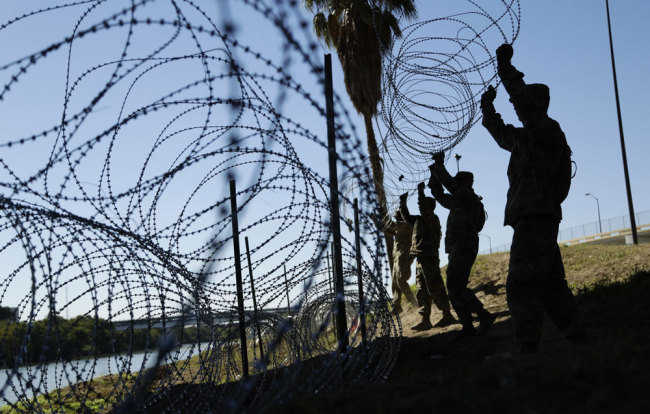 In this Friday, Nov. 16, 2018, file photo, members of the U.S. military install multiple tiers of concertina wire along the banks of the Rio Grande near the Juarez-Lincoln Bridge at the U.S.-Mexico border, in Laredo, Texas. [File photo: AP/Eric Gay]