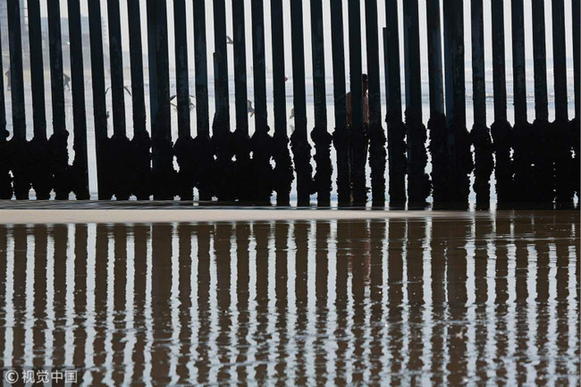 In this file photo taken on November 20, 2018 A man peers through the United States-Mexico Border fence in San Ysidro, California. [Photo: VCG]