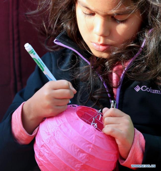 A girl makes a Chinese lantern during a celebration of Chinese Lunar New Year at the Original Farmers Market in Los Angeles, the United States, Feb. 17, 2019. [Photo: Xinhua]