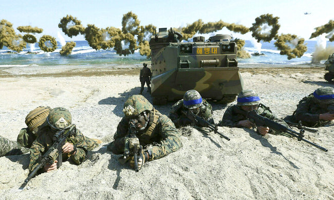 File Photo: Marines of the U.S., left, and South Korea, wearing blue headbands on their helmets, take positions after landing on a beach during the joint military combined amphibious exercise, called Ssangyong, part of the Key Resolve and Foal Eagle military exercises, in Pohang, South Korea, on March 12, 2016. [Photo: AP/Kim Jun-bum/Yonhap ]