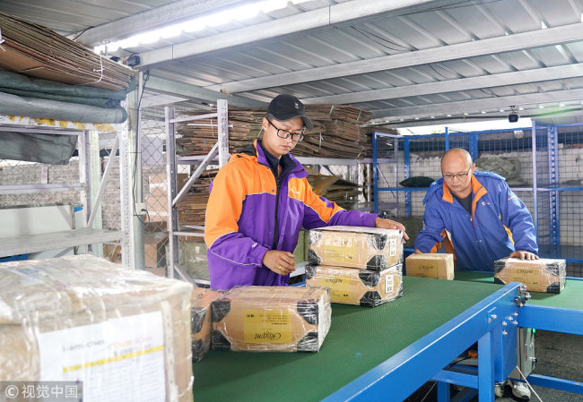 Employees sort parcels at a terminal distribution park in Beijing. [Photo: VCG]