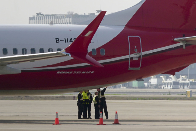 Ground crew chat near a Boeing 737 MAX 8 plane operated by Shanghai Airlines parked on tarmac at Hongqiao airport in Shanghai, China, Tuesday, March 12, 2019. U.S. aviation experts on Tuesday joined the investigation into the crash of an Ethiopian Airlines jetliner that killed 157 people, as a growing number of airlines grounded the new Boeing plane involved in the crash. [Photo: AP]