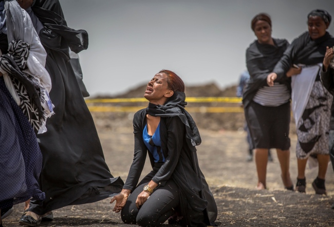 Ethiopian relatives of crash victims mourn and grieve at the scene where the Ethiopian Airlines Boeing 737 Max 8 crashed shortly after takeoff on Sunday killing all 157 on board, near Bishoftu, south-east of Addis Ababa, in Ethiopia Thursday, March 14, 2019. The French air accident investigation authority said Thursday that it will handle the analysis of the black boxes retrieved from the crash site and they have already arrived in France but gave no time frame on how long the analysis could take. [Photo via AP/Mulugeta Ayene]