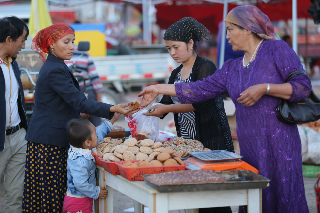 Muslims buy food at a market to celebrate the Corban Festival. [Photo: IC]