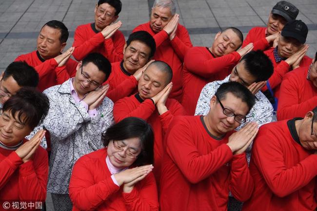 With the 2019 World Sleep Day on its way, several members of the Chongqing Sleeping Association wear pajamas and post sleeping gestures on the road as a form of performance art to draw public's attention to sleep habits and sleep quality improvement, Chongqing, March 16, 2019. [Photo:VCG]