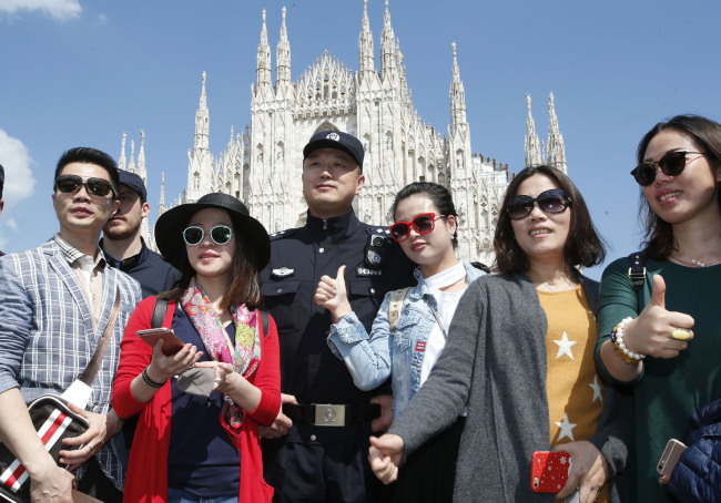 A Chinese Police officer poses with Chinese tourists in front of Milan's gothic cathedral, Italy, Tuesday, May 3, 2016. Chinese policemen were in Italy to start patrols with Italian officers in Rome and Milan in a two-week experiment. [File Photo: IC]