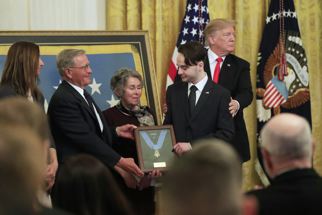 President Donald Trump awards the Medal of Honor to Army Staff Sgt. Travis Atkins and joins Atkin's son Trevor Oliver, right, and his parents John and Elaine Atkins of Bozeman, Mont., after accepting the posthumous recognition for conspicuous gallantry in Iraq in June 2007, in the East Room of the White House, Wednesday March 27, 2019, in Washington. [Photo: AP/Manuel Balce Ceneta]