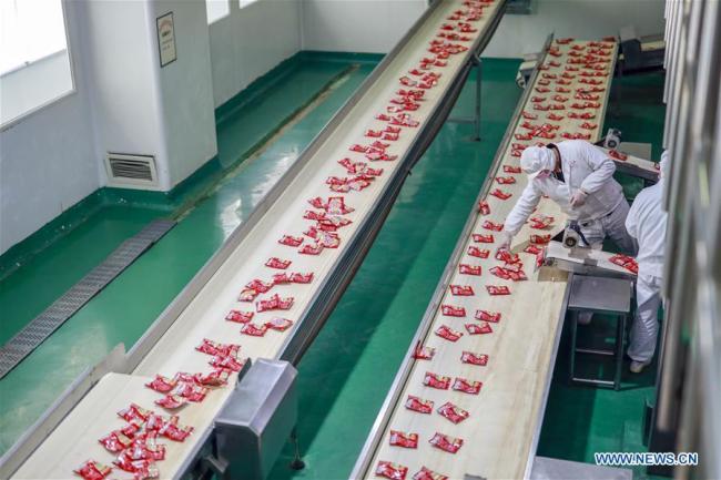 A woman works at a production line(生产线 shēngchǎnxiàn) of Fuling pickle in southwest China's Chongqing, Feb. 22, 2019. [Photo: Xinhuag]