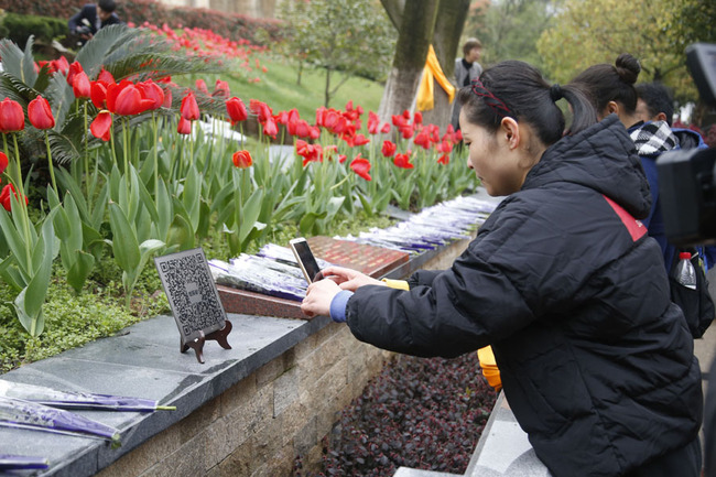 A woman scans the QR code on a tomb to send virtual offering to the dead in Hangzhou, Zhejiang Province on Mar 29, 2019. By scanning the code, people can also know the appearance and life of the deceased. [Photo: IC]