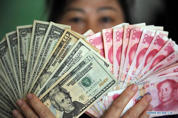 A residents shows China's yuan and US dollar banknotes in Qionghai, South China's Hainan province, January 7, 2016. [Photo: Xinhua]