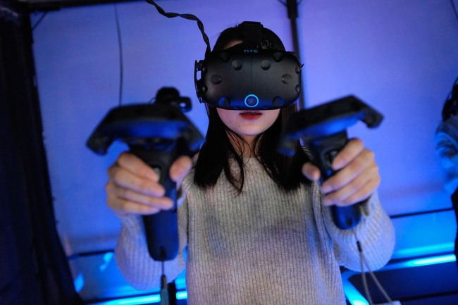 In this photo taken on February 13, 2019, a woman plays a video game using a virtual-reality headset at an arcade in Shanghai. [Photo: AFP/Lianchao Lan]