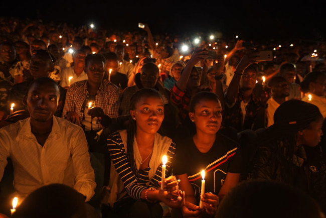 Rwandans sitting in the stands hold candles as part of a candlelit vigil during the memorial service held at Amahoro stadium in the capital Kigali, Rwanda Sunday, April 7, 2019. [Photo: AP/Ben Curtis]