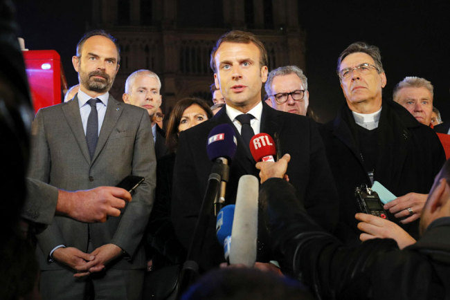 French President Emmanuel Macron (C) is accompanied by Mayor of Paris Anne Hidalgo (3L), French Prime Minister Edouard Philippe (L), French Culture Minister Franck Riester (2L) and Archbishop of Paris Michel Aupetit as he speaks at Notre-Dame Cathedral in Paris on April 15, 2019, after a fire engulfed the building. [Photo: Pool/AFP/Philippe Wojazer]